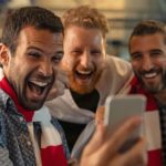 Sports fans looking at smart phone representing surging pointsbet share price