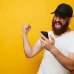 man looking at mobile phone and cheering representing surging asx share price