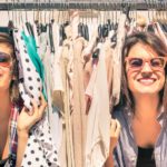 Two happy shoppers finding bargains amongst clothes on a store rack