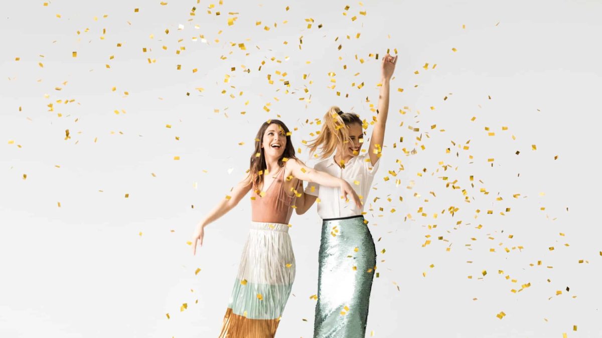 Two fashionable asx investors dancing among confetti.