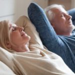 Retired couple reclining on couch with eyes closed