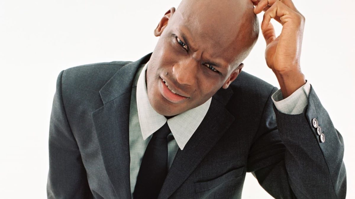 A man scratches his head in confusion., indicating mixed share price movement on the ASX