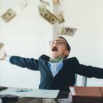 A young entrepreneur boy catching money at his desk, indicating growth in the ASX share price or dividends