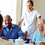 healthcare worker overseeing group of aged care residents at table