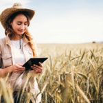 Agricultural ASX share price on watch represented by farmer in field looking at tablet computer.