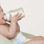 A happy baby drinking milk from a bottle