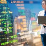 Young man with laptop watching stocks and trends while thinking