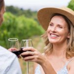 A happy couple drinking red wine in a vineyard as the Treasury Wine share price rises today