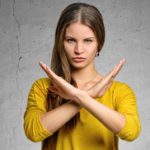 A woman crosses her hands in front of her body in a defensive stance indicating a trading halt.