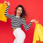 a happy young woman holding multiple shopping bags