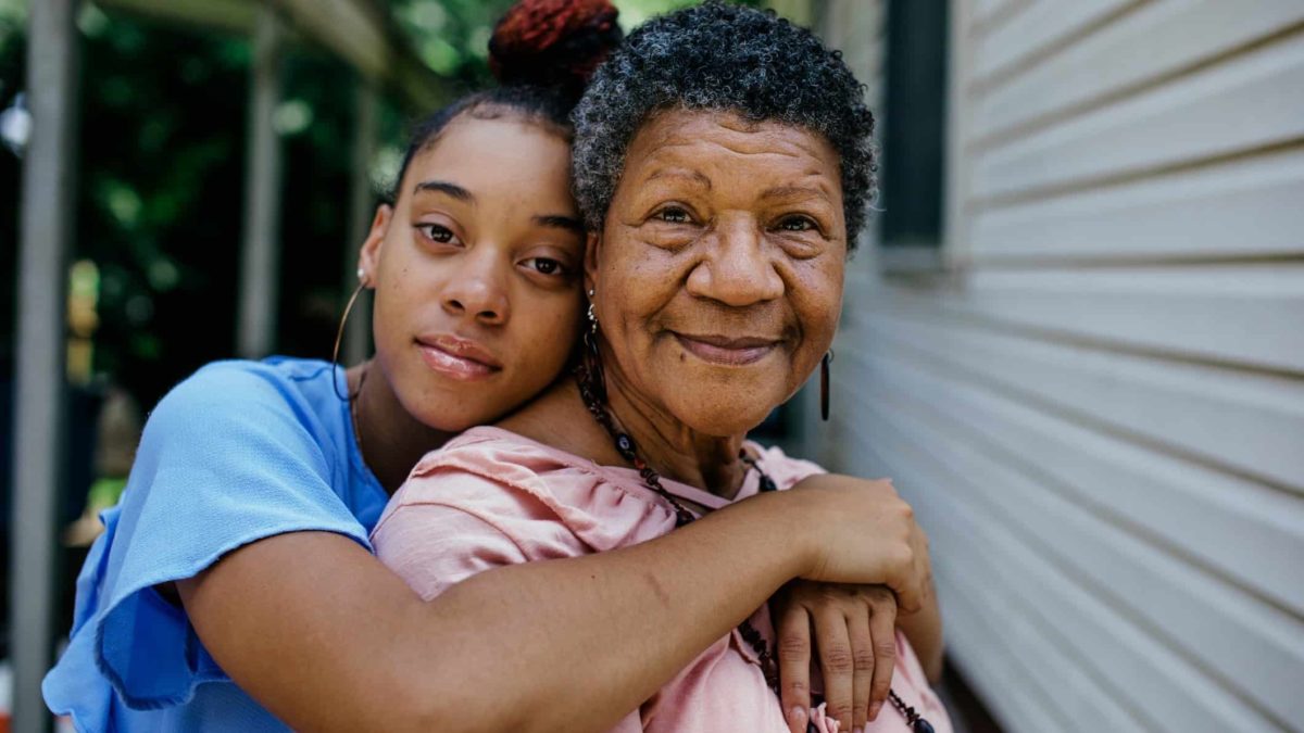 Girl and her grandmother sharing a hug on the porch