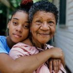 Girl and her grandmother sharing a hug on the porch