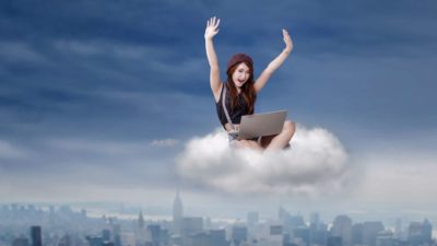 Woman using laptop sitting in cloud cheering