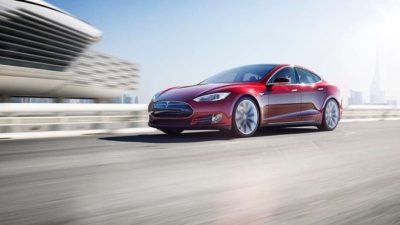 red Tesla being driven on the road