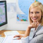 A smiling travel agent sitting at her desk working for Corporate Travel Management