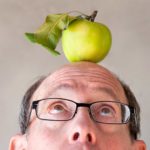 man looks up at apple on his head