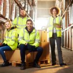 Logistic workers sitting amid pallets and stock in a warehouse.