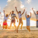 group of friends jump on the beach