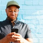 man looks at phone while disappointed