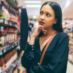 A woman ponders over what to buy as she looks at the shelves of a supermarket.