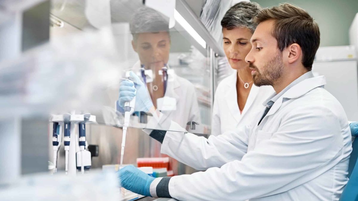 Medical technicians wearing white medical coats conduct a test in a laboratory.