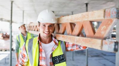 Construction workers carry big steel beam