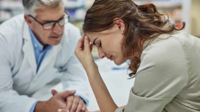 a doctor comforts a sad patient by holding her hand in a healthcare setting.