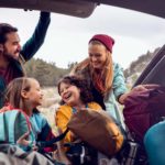 family taking gear out of back of car for camping