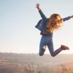 Woman jumping for joy at great news with wide open country around her.