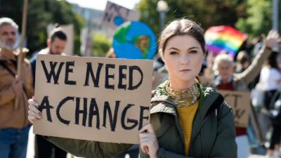 woman holds sign saying 'we need change' at climate change protest