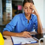 Female worker sitting desk with head in hand and looking fed up