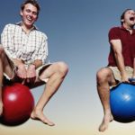 Two men laughing while bouncing on bouncy balls