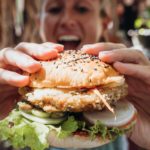 woman holding out vegan burger about to eat