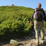 A mountaineer takes a rest while climbing a green mountain.