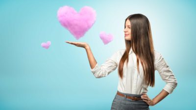 A satisfied business woman with three fluggly pink clouds in the shape of a heart