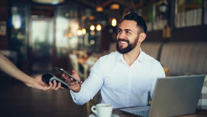 A happy man using PayPal to pay.