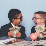 Two boys in business suits holding handfuls of money