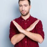 A man stands with his arms crossed in an X shape.