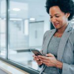 A female executive smiles as she carries out business on her mobile phone.