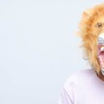 A person wears a roaring lion mask.