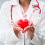 A medical specialist holds a red heart connected via technology and artificial intelligence (AI)