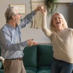 An older couple dance in their living room as they enjoy their retirement funded by ASX dividends