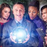 a group of people stand examining a large glowing cystral ball held in the hands of one of the group members while the others regard it with various expressions of wonder, curiousity and scepticism.