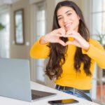 Young woman using computer laptop smiling in love showing heart symbol and shape with hands. as she switches from a big telco to Aussie Broadband which is capturing more market share