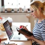 A female investor sits at her messy desk and marks dates in her diary for Zip announcements in 2022