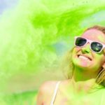 A woman has a big smile on her face as she gets green paint powder tipped all over her.