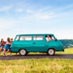 A group of friends push their van up the road on an Australian road.