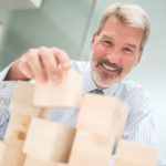 A businessman stacks building blocks.