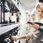 Couple look at a bottle of wine while trying to decide what to buy.