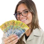 Woman holding $50 notes and smiling.